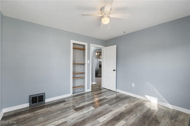 empty room featuring ceiling fan, dark hardwood / wood-style floors, and built in shelves