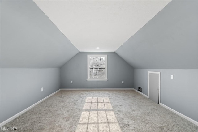 additional living space featuring vaulted ceiling and light carpet