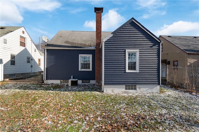 back of house featuring central air condition unit and a lawn