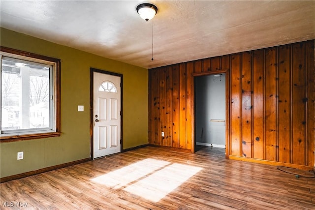 entrance foyer with light wood-type flooring and wood walls