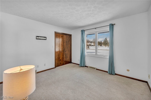 carpeted spare room featuring a textured ceiling