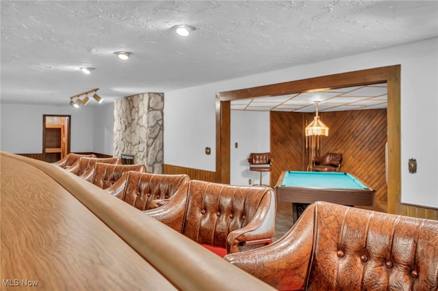 interior space featuring pool table, wood walls, and a textured ceiling