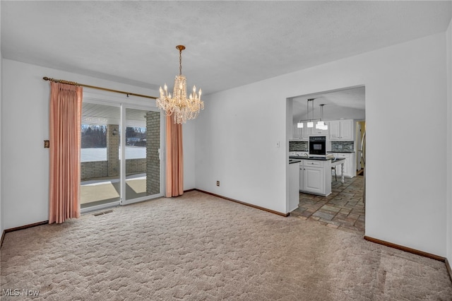 unfurnished living room featuring light colored carpet, an inviting chandelier, and a textured ceiling