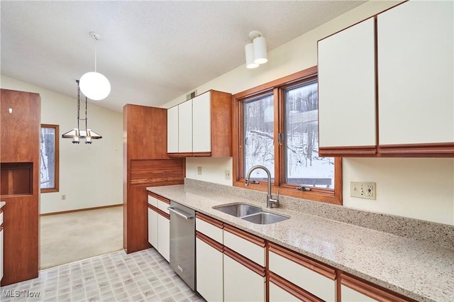 kitchen with hanging light fixtures, light stone countertops, sink, white cabinetry, and stainless steel dishwasher