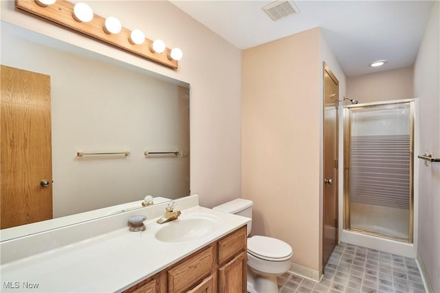 bathroom featuring toilet, a shower with door, and vanity