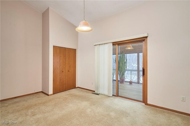 spare room with high vaulted ceiling and light carpet