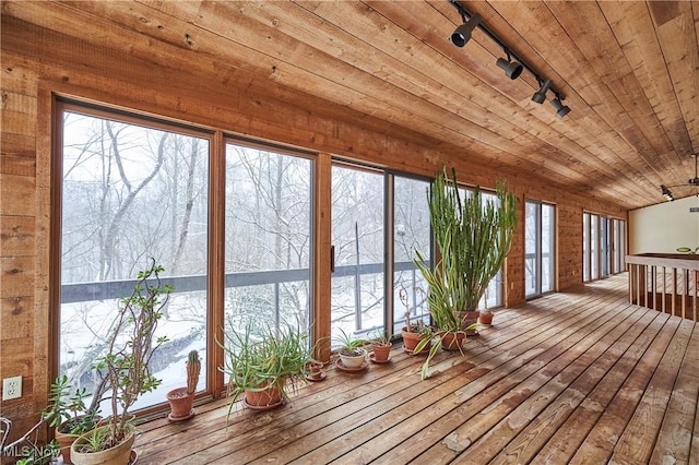 unfurnished sunroom featuring track lighting, wooden ceiling, and a water view