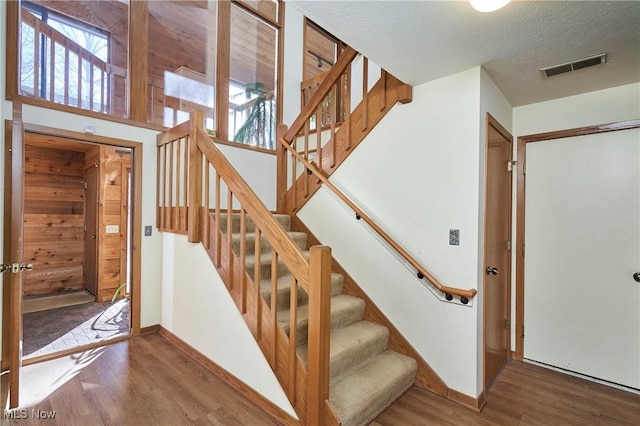 staircase featuring a healthy amount of sunlight, hardwood / wood-style floors, and a textured ceiling