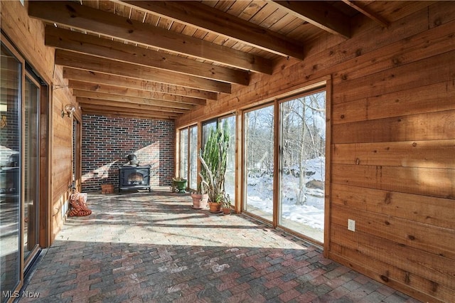 unfurnished sunroom with wooden ceiling, a wood stove, and beamed ceiling