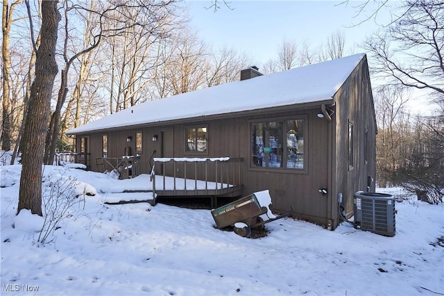 snow covered rear of property featuring covered porch and central AC unit