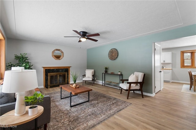 living room featuring ceiling fan, light hardwood / wood-style flooring, and a high end fireplace