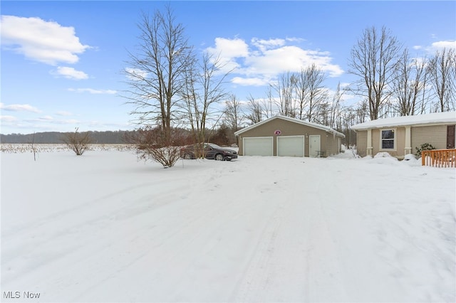 snowy yard with a garage and an outdoor structure