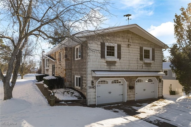 view of snowy exterior featuring a garage