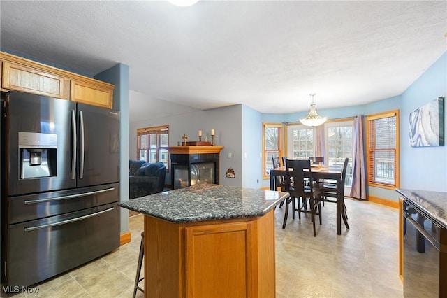 kitchen featuring decorative light fixtures, a center island, black dishwasher, dark stone countertops, and stainless steel fridge with ice dispenser