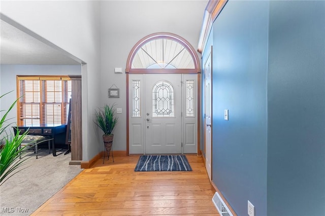 foyer with a towering ceiling and light hardwood / wood-style flooring