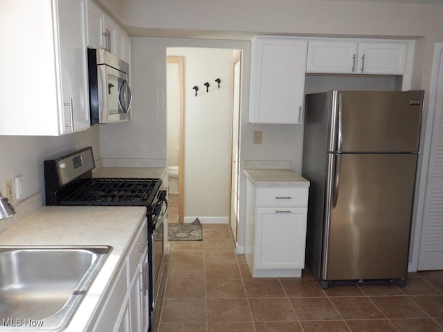 kitchen featuring sink, dark tile patterned floors, white cabinets, and appliances with stainless steel finishes