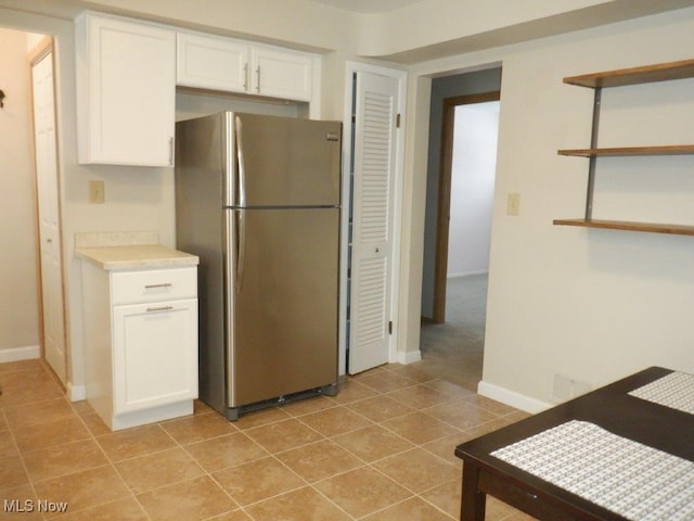 kitchen featuring white cabinets, stainless steel refrigerator, and light tile patterned floors