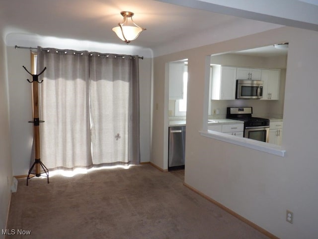 kitchen featuring white cabinets, appliances with stainless steel finishes, and light carpet