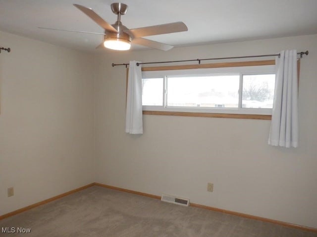 carpeted spare room with ceiling fan and plenty of natural light