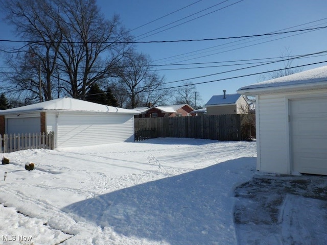 snowy yard with a garage and an outdoor structure