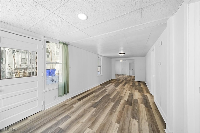 unfurnished living room featuring hardwood / wood-style flooring and a drop ceiling