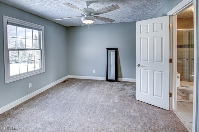 empty room featuring a textured ceiling, ceiling fan, and light colored carpet