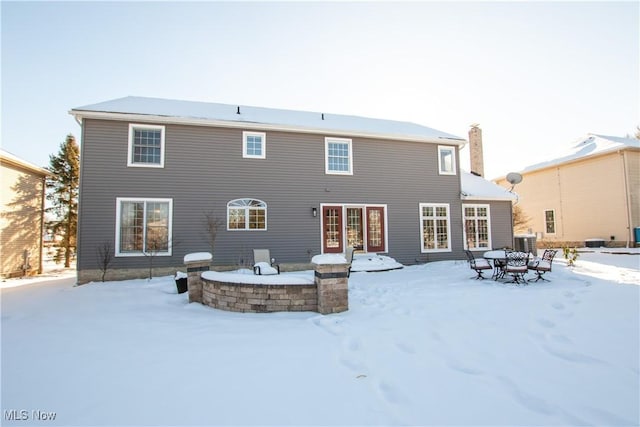 snow covered house featuring central AC