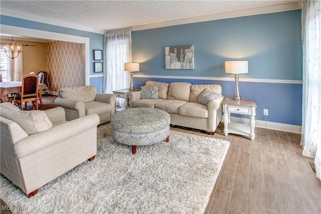 living room with ornamental molding, hardwood / wood-style floors, an inviting chandelier, and a textured ceiling