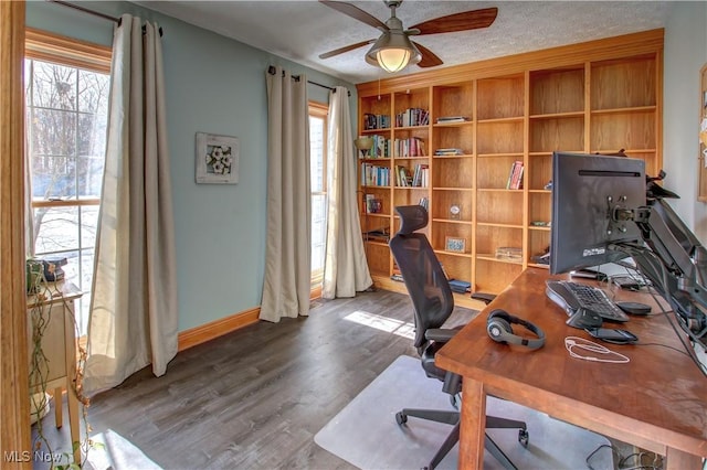 home office with ceiling fan, a wealth of natural light, dark hardwood / wood-style floors, and a textured ceiling