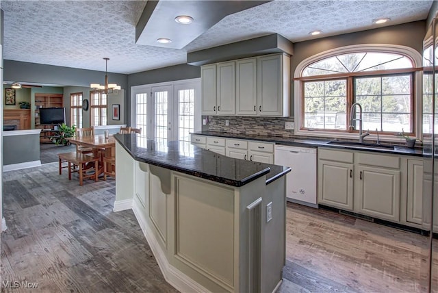 kitchen with sink, dishwasher, dark hardwood / wood-style floors, plenty of natural light, and a notable chandelier