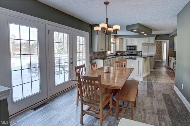 dining room featuring a textured ceiling, a notable chandelier, sink, and hardwood / wood-style flooring