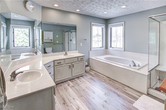 full bathroom with toilet, hardwood / wood-style flooring, a textured ceiling, independent shower and bath, and vanity