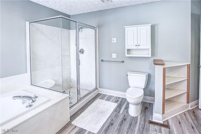 bathroom with toilet, a textured ceiling, hardwood / wood-style floors, and separate shower and tub