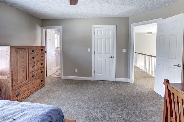 bedroom with ensuite bathroom, a textured ceiling, ceiling fan, and light carpet