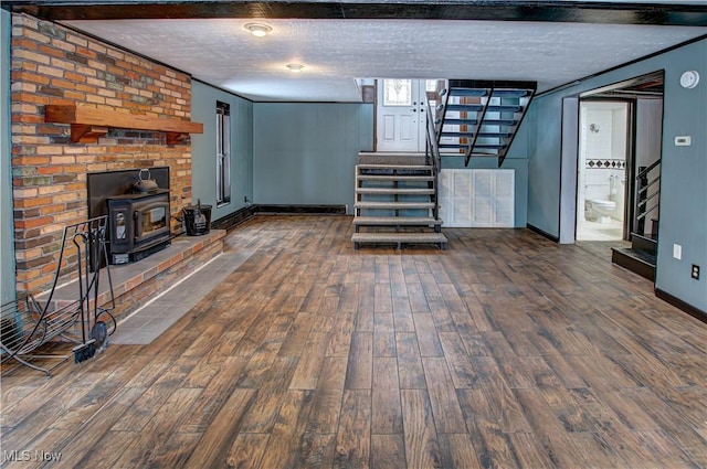 basement with a textured ceiling, crown molding, a wood stove, and dark hardwood / wood-style floors