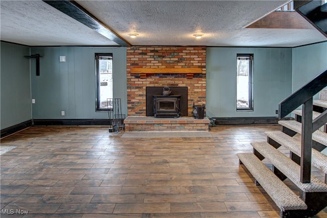 unfurnished living room featuring dark hardwood / wood-style flooring, a textured ceiling, and a wood stove