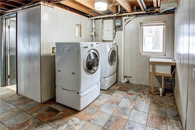 clothes washing area with separate washer and dryer, electric panel, and wooden walls