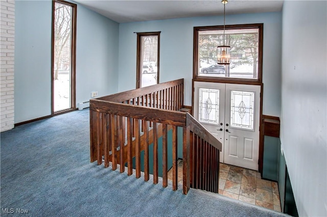 carpeted foyer with french doors, a healthy amount of sunlight, a chandelier, and baseboard heating