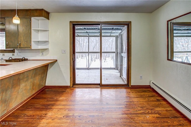 kitchen with dark hardwood / wood-style flooring, hanging light fixtures, plenty of natural light, and a baseboard heating unit