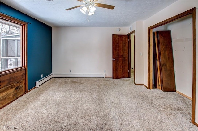 carpeted empty room featuring ceiling fan, a textured ceiling, and a baseboard heating unit