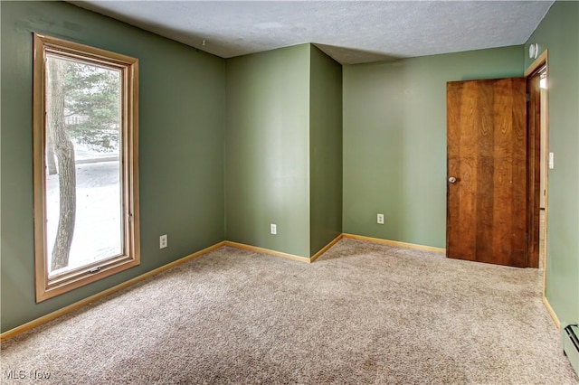 carpeted empty room featuring a baseboard heating unit and a textured ceiling