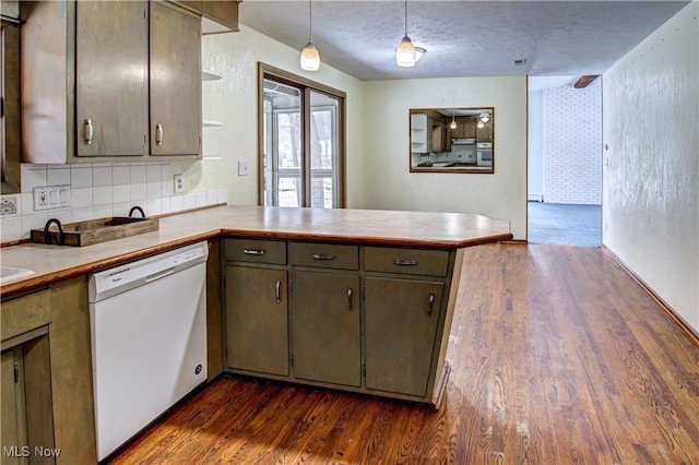 kitchen featuring dark hardwood / wood-style floors, decorative backsplash, hanging light fixtures, white dishwasher, and kitchen peninsula