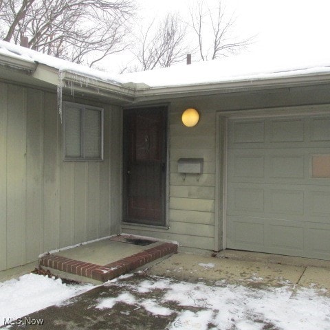 snow covered property entrance with a garage