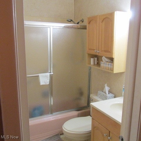 full bathroom featuring toilet, combined bath / shower with glass door, and vanity