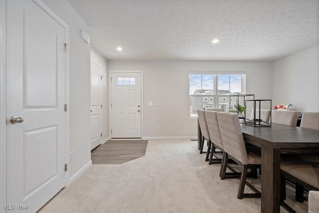 carpeted dining area featuring a textured ceiling