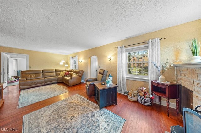 living room featuring a fireplace, a textured ceiling, and dark hardwood / wood-style floors