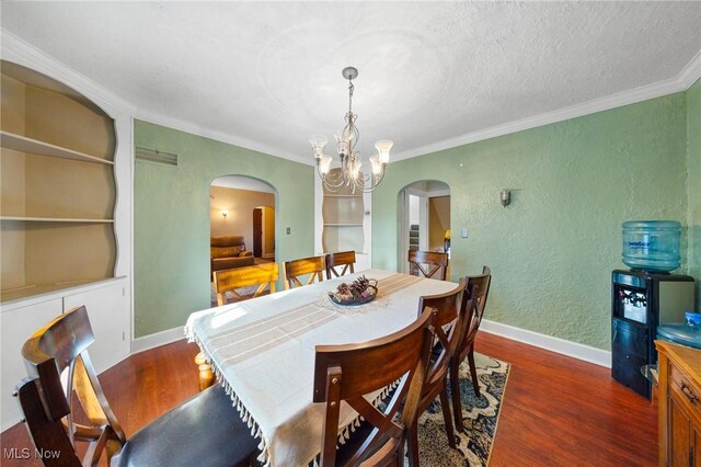 dining space featuring dark hardwood / wood-style flooring, built in features, ornamental molding, and a chandelier