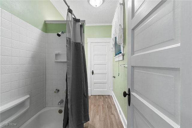 bathroom with shower / bathtub combination with curtain, hardwood / wood-style floors, ornamental molding, and a textured ceiling