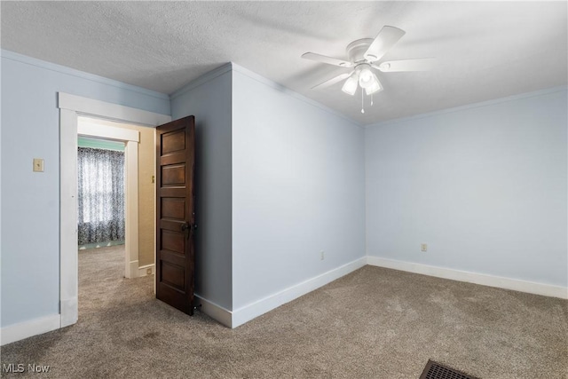 spare room with a textured ceiling, ceiling fan, carpet, and crown molding