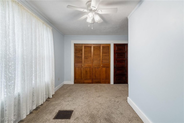 unfurnished bedroom with carpet flooring, a textured ceiling, ceiling fan, ornamental molding, and a closet